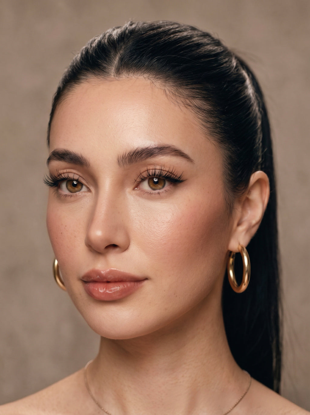 A close-up portrait of a woman with dark hair pulled back, wearing instant glam mermaid style self adhesive lash edit collection lash clusters.