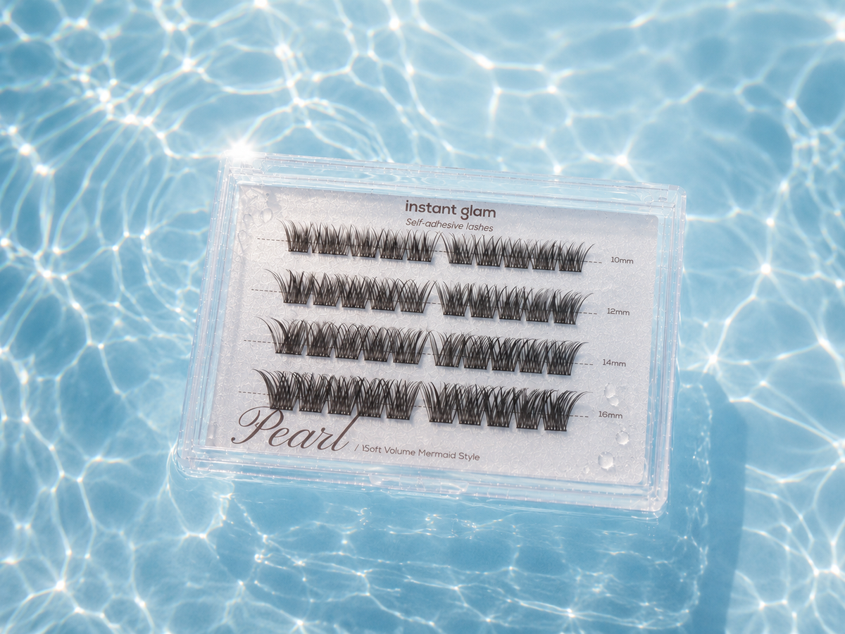 A set of self adhesive eyelash clusters in a clear plastic tray labeled 'instant glam Pearl', placed on a bright blue water surface with rippling light reflections.